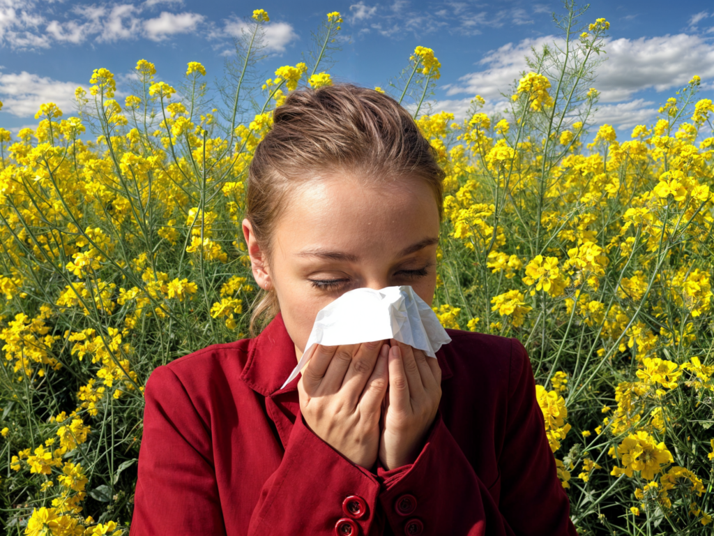 Woman with allergies blowing her nose in field of flowers