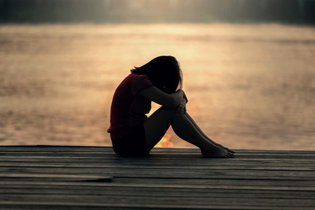 depressed girl on dock at sunset