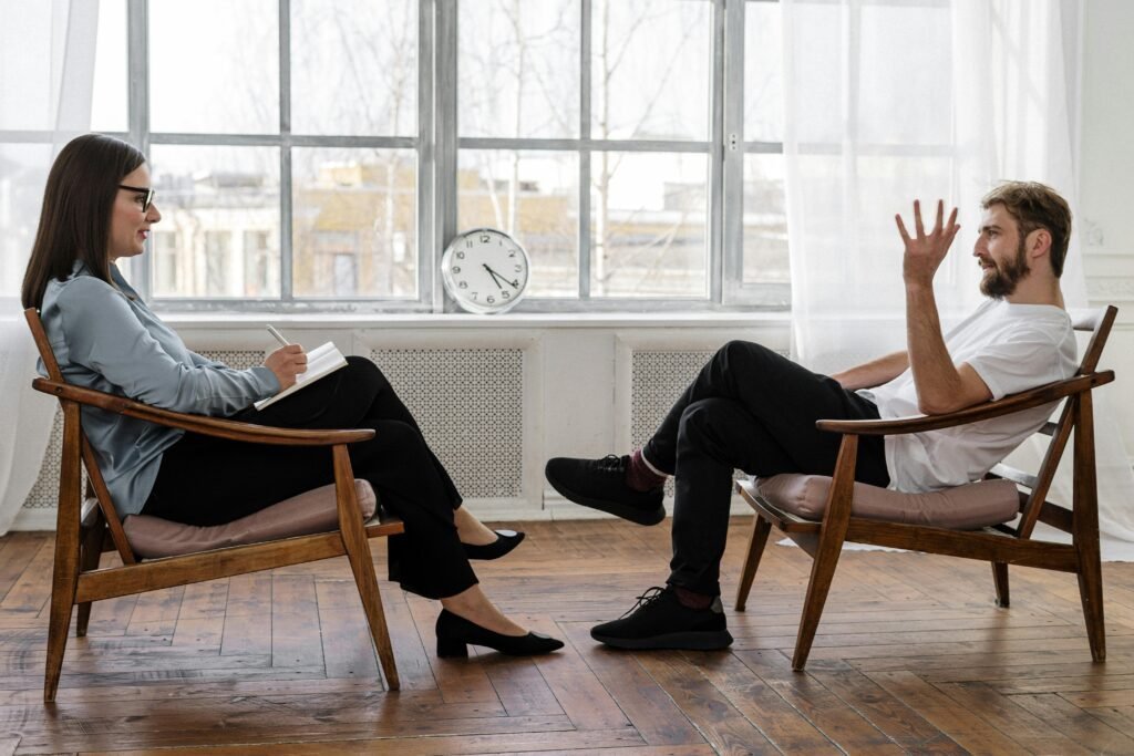 Man and woman sitting in chairs facing each other for therapy session 